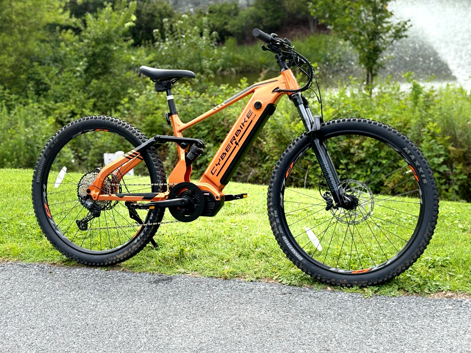 Three-quarter view of the orange Cyberbike Raptor showing its integrated battery, mid-drive motor and full-suspension frame